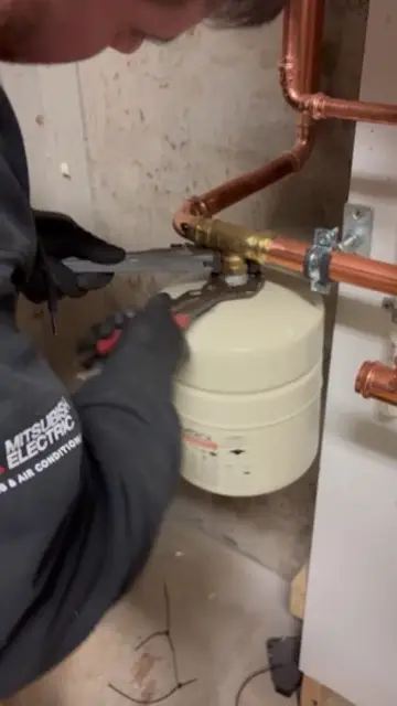 Expansion tank connected to copper plumbing lines in a mechanical room