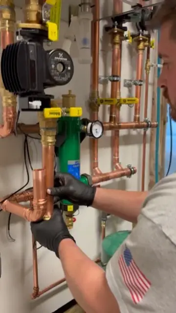 Technician adjusting copper piping, valves, and pressure components