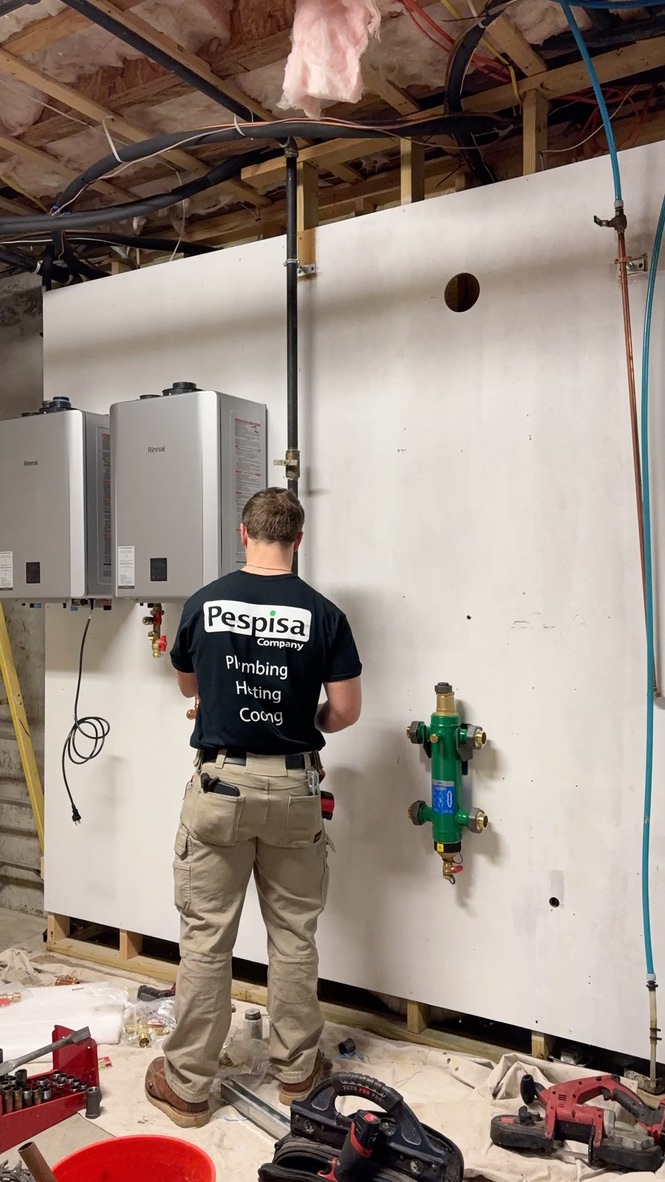 Pespisa technician working on wall-mounted tankless heating equipment and piping