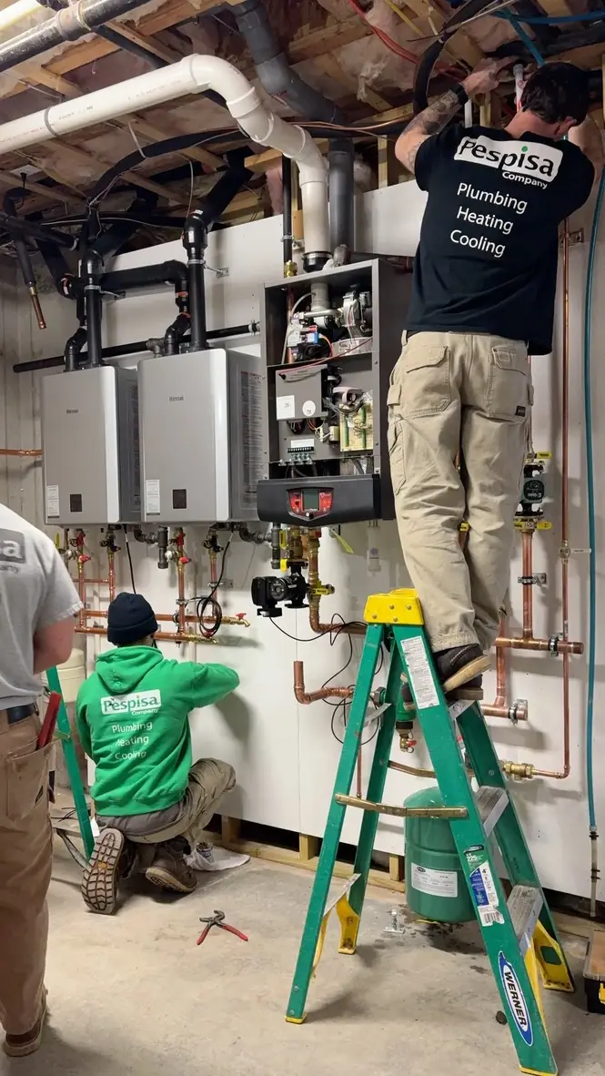Technicians installing wall-mounted heating equipment in a mechanical room