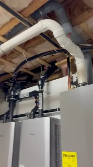 Black piping connected above a wall-mounted heating unit