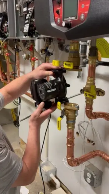 Close-up of hands adjusting a valve on a copper piping system