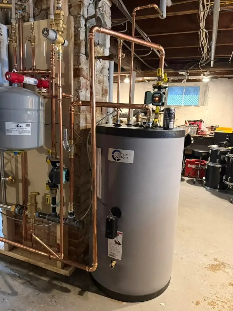 New hot water storage tank with copper piping, pumps, and an expansion tank in a basement