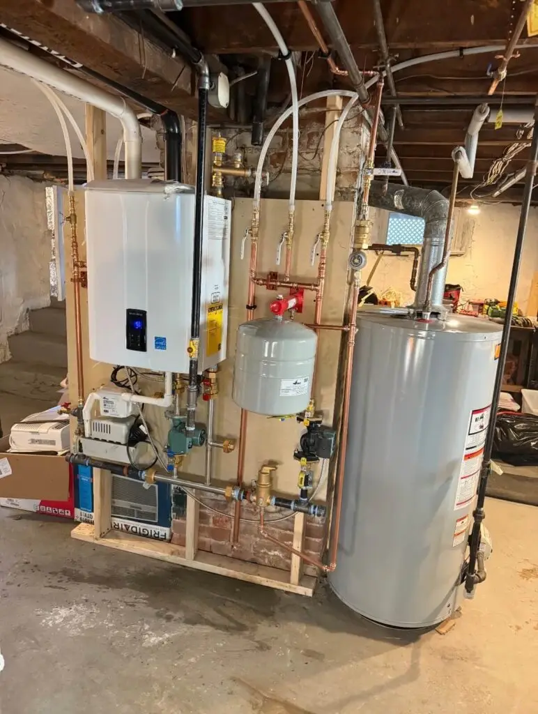 New wall-mounted boiler and hot water tank installation with copper piping and expansion tanks