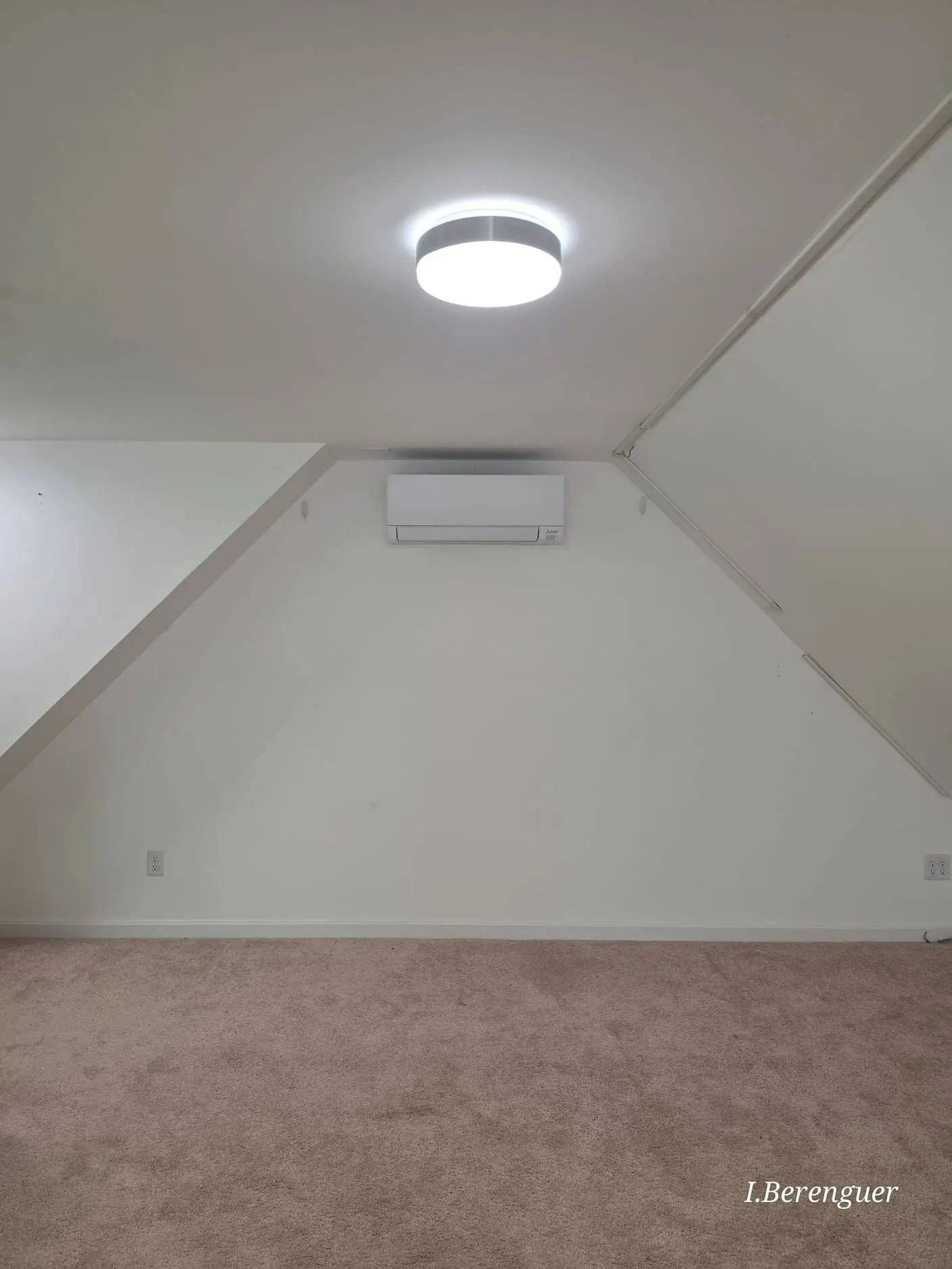 Wall-mounted Mitsubishi mini-split in a finished third-floor room with sloped ceilings